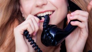 Black telephone is being used by a Laughing Lady to communicate with someone.