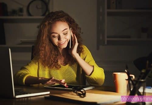 A woman working on a Mommy Sex Line was seated with a full tab, phone, and laptop.