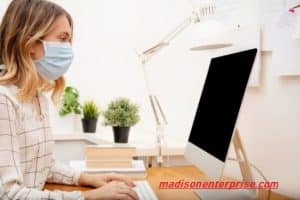 A lovely woman is sitting in the chair, using the technology, and donning the mask.