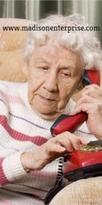 A sexy grandmother is conversing on the phone while sitting on the couch and having a lot of wrinkles.