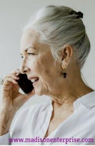 A grandmother is performing sex line tasks while standing on the floor. She looks seductive. She is seducing someone for sex purposes.