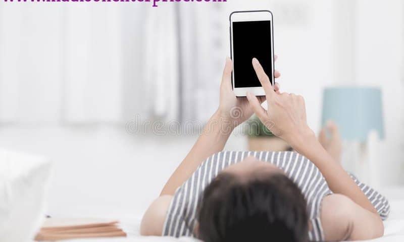 She is lying on the floor with a touching phone while donning a dress with a line design.